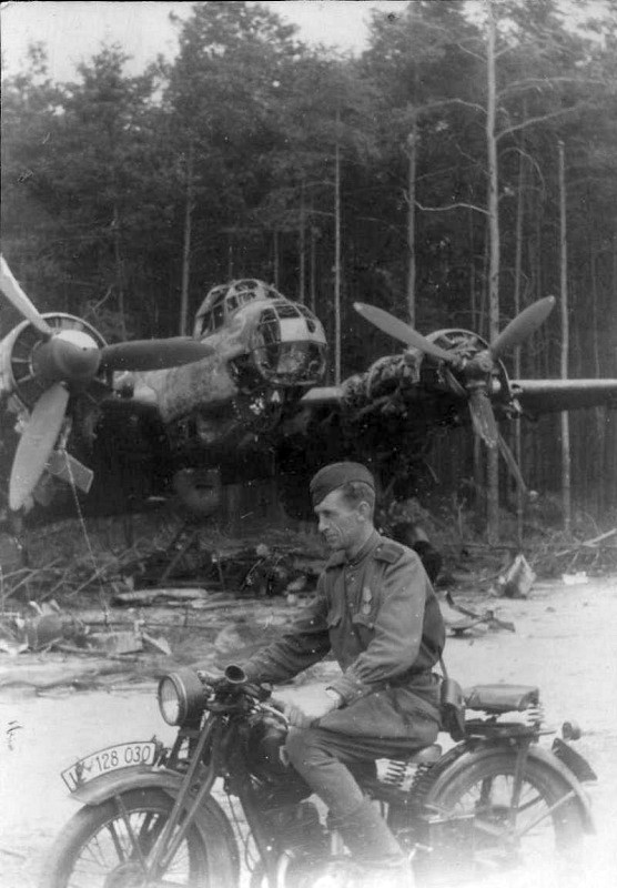 foto Russian master sergeant on the trophy motorcycle near broken Ju-88